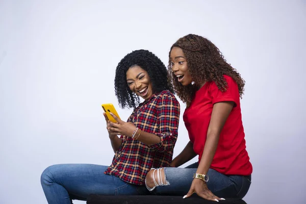 两个年轻美丽的黑人女子坐在一起 看着电话 感到兴奋 — 图库照片