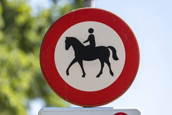 WIERDEN, NETHERLANDS - Aug 06, 2020: Round traffic sign with round warning circle and a depicted horseback rider with half of the frame blue sky and half greenery in the background — Stock Image Wierden Netherlands Aug 2020 Traffic Sign Warning Circle Depicted Horseback Royalty Free Stock Photos