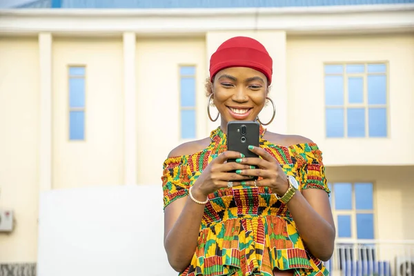 아프리카의 여성이 밖에서 웃으면서 전화를 사용하는 — 스톡 사진