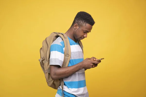 Een Jonge Afrikaanse Man Met Een Rugzak Met Zijn Telefoon — Stockfoto