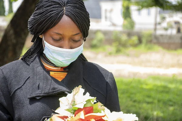 黒い女性の喪のショットは マスクを着用し 花を保持 新しい通常の概念 — ストック写真