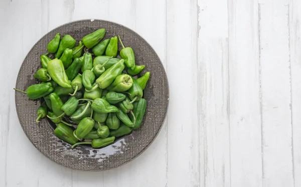 Ovanifrån Padron Paprika Mörk Keramisk Platta Vit Trä Bakgrund — Stockfoto