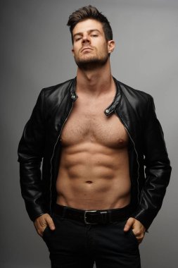 A portrait of a sexy young guy with a muscular body in a biker jacket clipart