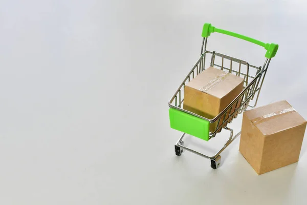 Minyatür Bir Alışveriş Arabasında Beyaz Bir Yüzey Üzerinde Küçük Kartonların — Stok fotoğraf