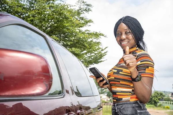 Uma Jovem Negra Perto Carro Sorrindo Segurando Seu Telefone Polegar — Fotografia de Stock