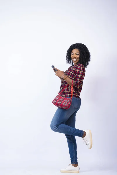 一个黑色女性拿着手提包 拿着手机 兴奋而快乐的垂直镜头 — 图库照片