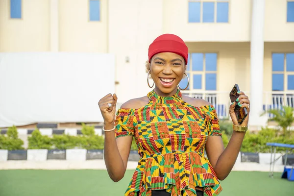 Uma Jovem Mulher Africana Bonita Sorrindo Enquanto Segura Seu Telefone — Fotografia de Stock