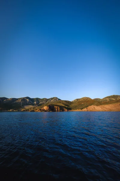 Sebuah Gambar Vertikal Dari Laut Biru Dengan Bukit Latar Belakang — Stok Foto
