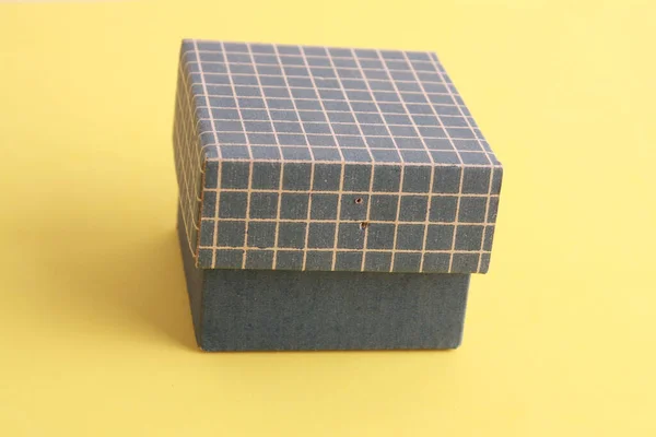 Zbliżenie Ujęcia Małego Niebieskiego Kartonowego Pudełka Żółtym Tle — Zdjęcie stockowe