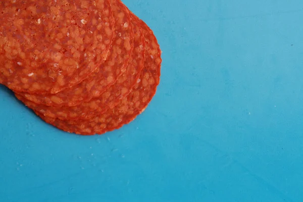 Cuatro Rebanadas Salami Sobre Una Superficie Azul — Foto de Stock