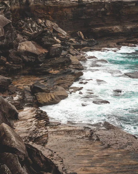 悲観的な日に青い水の横にある大きな崖の美しい垂直ショット 壁紙に最適です — ストック写真