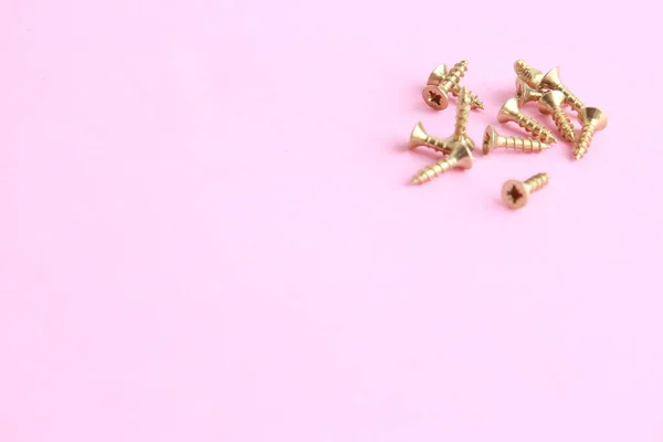粉色表面上的金色星形螺丝 — 图库照片