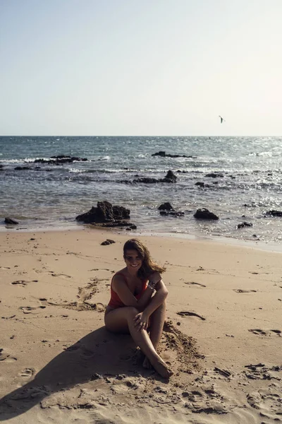 西班牙罗塔海滩上坐着一位漂亮的女性 身穿泳衣 面带微笑的纵向照片 — 图库照片