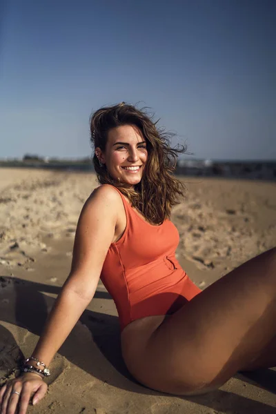 在一个刮风的日子里 一个美丽的女性坐在西班牙罗塔海滩上 身穿泳衣的纵向照片 — 图库照片