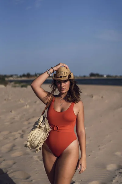西班牙罗塔海滩上 一位身穿泳衣 头戴一顶帽子的漂亮女性在多风的天气里的照片 — 图库照片