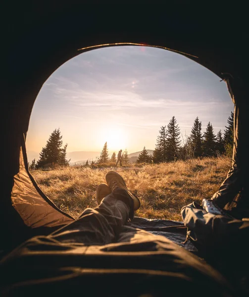テントに寝そべって夕日の美しい景色を楽しむ人 — ストック写真