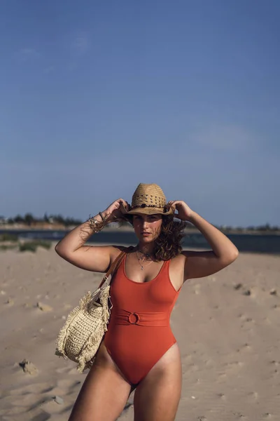 西班牙罗塔海滩上 一位身穿泳衣 头戴一顶帽子的漂亮女性在多风的天气里的照片 — 图库照片