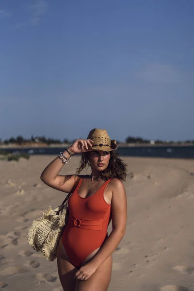 風の強い日にスペインのロタビーチで水着と帽子を身に着けている美しい女性の垂直ショット — ストック写真