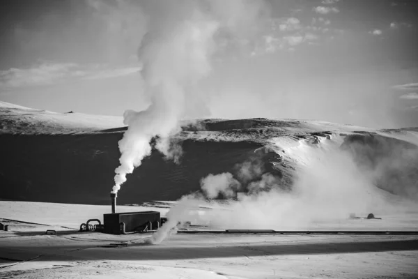 煙突から煙が出てくる雪原の小さな金属ボイラー工場のグレースケールショット — ストック写真