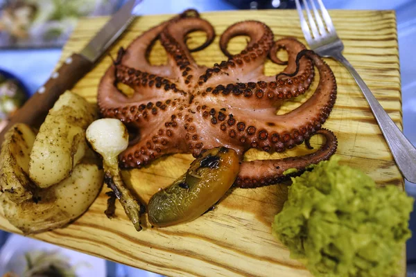 A closeup of a cooked octopus served in a wooden plate