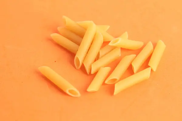 Selective Focus Shot Pile Raw Penne Regatta Pasta Orange Surface — Stock Photo, Image