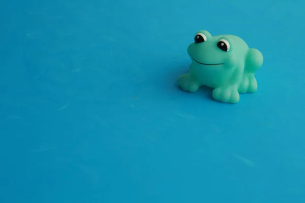 一只绿色玩具青蛙的特写镜头 用于蓝色背景的浴缸 — 图库照片