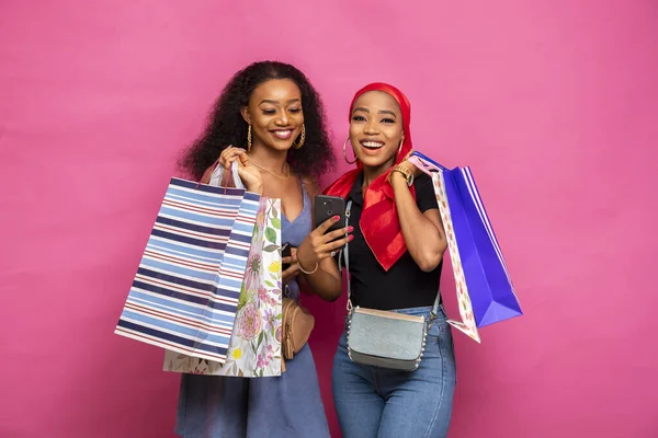 Dwie Młode Afrykanki Niosące Torby Zakupy Oglądające Zawartość Razem Przez — Zdjęcie stockowe