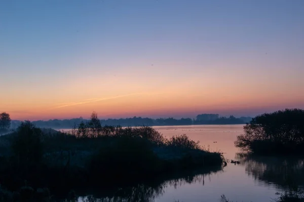 Piękne Ujęcie Drzewiastych Sylwetek Jeziorze Kolorowym Zachodem Słońca Tło Nieba — Zdjęcie stockowe