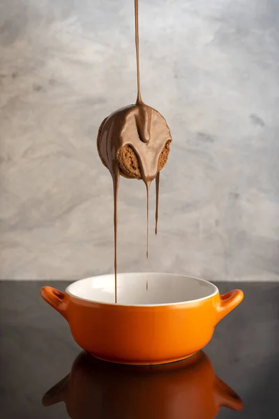 Vertikální Záběr Chutné Sušenky Která Pokryta Čokoládou Nad Oranžovou Miskou — Stock fotografie