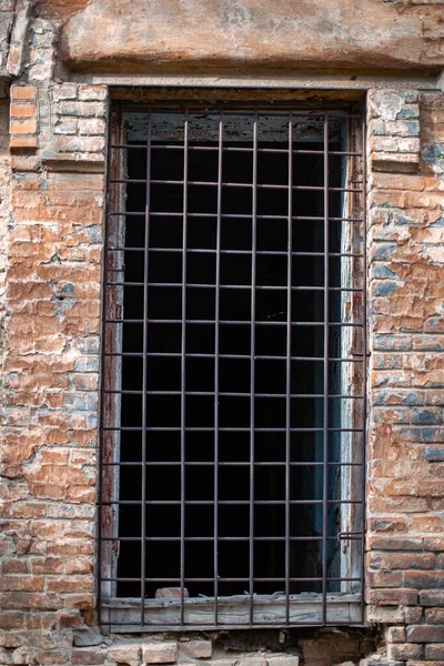 鉄の棒を持つ古い放棄されたレンガ造りの建物の窓の垂直ショット — ストック写真