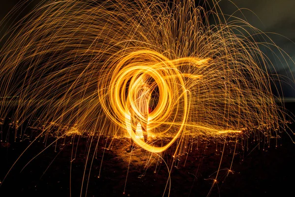 An amazing steel wool fire circles at night with glowing sparks