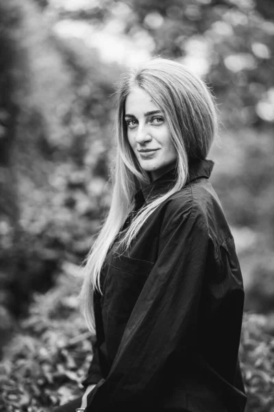 一张灰色的照片 是一个时髦的高加索金发女子在绿树成荫的环境下摆出的姿势 — 图库照片
