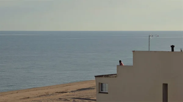 一个女人站在阳台上看着美丽的大海 — 图库照片