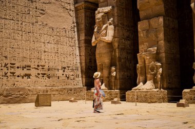 A closeup shot of a female standing in front of a Medinet Habu temple in Egypt clipart