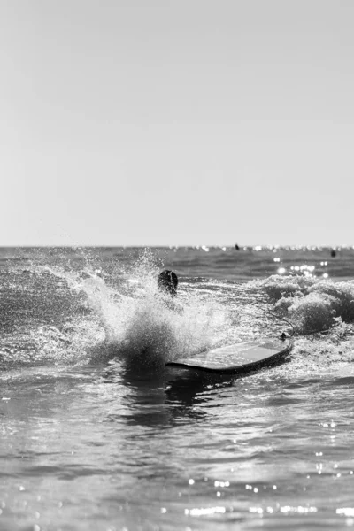 水の中の女性とサーフィンボードの垂直グレースケールショット — ストック写真