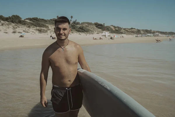 Atrakcyjny Młody Mężczyzna Bez Koszulki Trzymający Deskę Surfingową Plaży — Zdjęcie stockowe