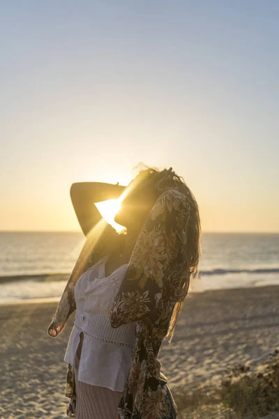 一个有着美丽长发的年轻女子在日落时高高兴兴地摆姿势拍照的垂直照片 — 图库照片