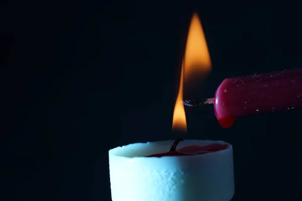 A closeup shot of a candle. Lighting a candle with another candle