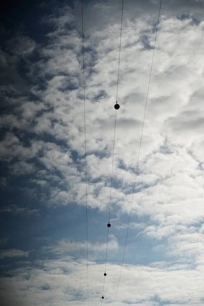Вертикальный Снимок Электрических Линий Облачное Небо Над Ним — стоковое фото