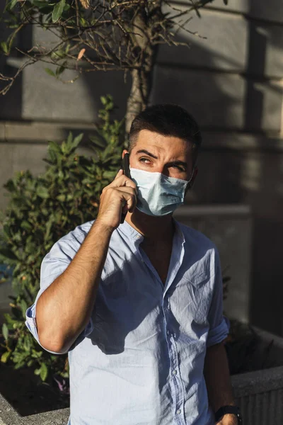 Ένας Νεαρός Άνδρας Ιατρική Μάσκα Που Μιλάει Στο Τηλέφωνο Έννοια — Φωτογραφία Αρχείου