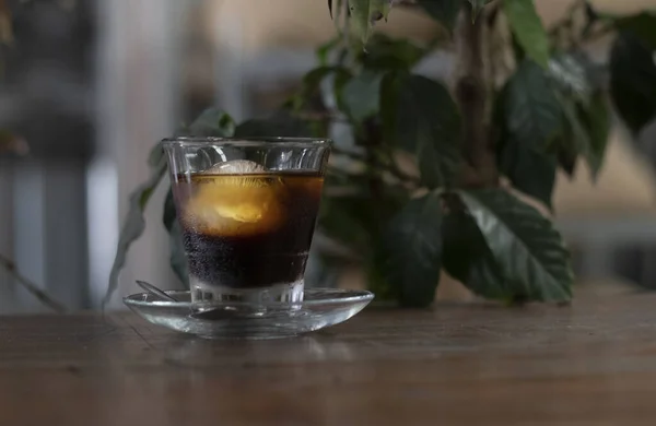 Ένα Ποτήρι Παγωμένο Μαύρο Καφέ Ένα Τραπέζι Καφέ Φυτά — Φωτογραφία Αρχείου