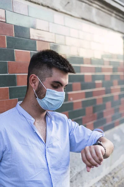 Een Jonge Man Met Een Medisch Masker Kijkt Naar Zijn — Stockfoto