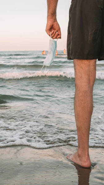 Tiro Vertical Homem Segurando Uma Máscara Médica Perto Mar Novo — Fotografia de Stock