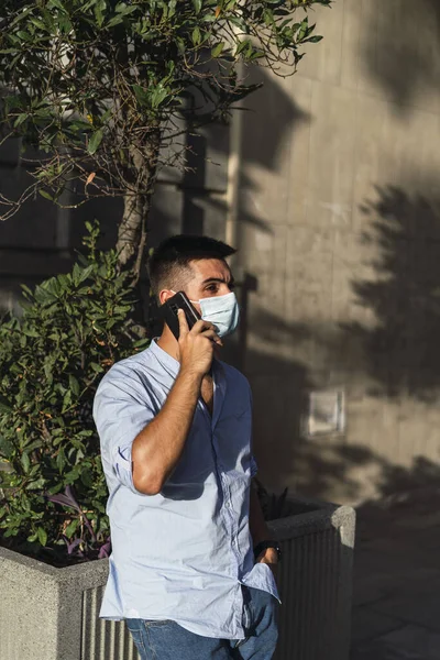 Een Jonge Man Met Een Medisch Masker Aan Telefoon Het — Stockfoto