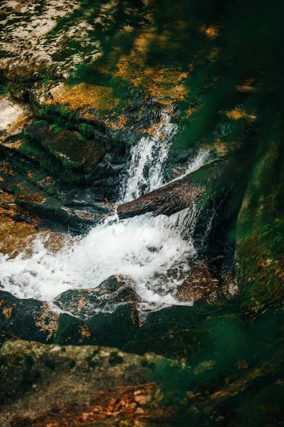 Vertikální Záběr Malého Vodopádu Slunečním Světlem Vodě Mechem Pokrytých Kamenech — Stock fotografie