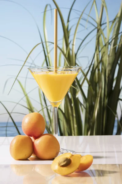 Eine Vertikale Aufnahme Eines Cocktailglases Mit Einem Strohhalm Neben Aprikosen — Stockfoto