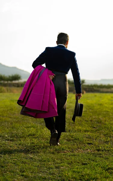 A vertical shot of a toreador walking along  the field