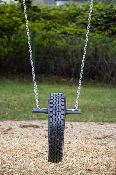 A vertical shot of a tire swing in a playground