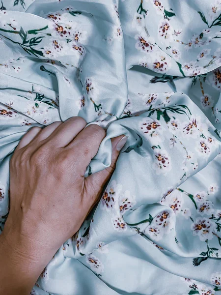 拍照一个人的手抓起有花的床单的垂直特写照片 — 图库照片