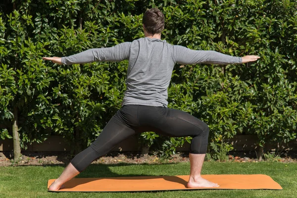 Ung Vältränad Man Utövar Yoga Och Gör Krigaren Poserar Utomhus — Stockfoto